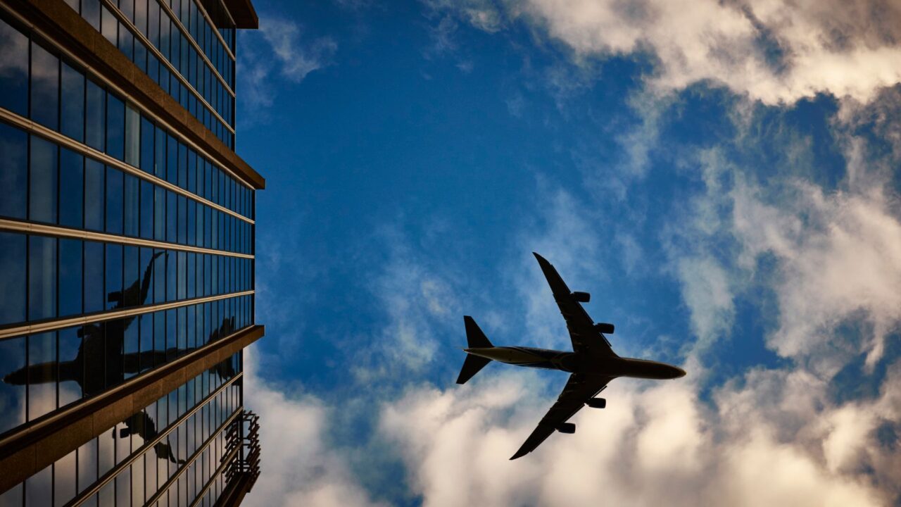 地上から空を飛ぶ飛行機を見上げている
